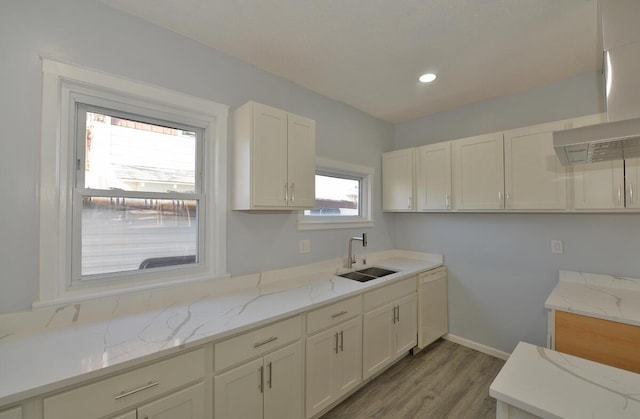 kitchen with sink, white cabinetry, white dishwasher, light stone counters, and light hardwood / wood-style floors