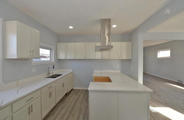 kitchen featuring light stone counters, island range hood, sink, and light hardwood / wood-style flooring