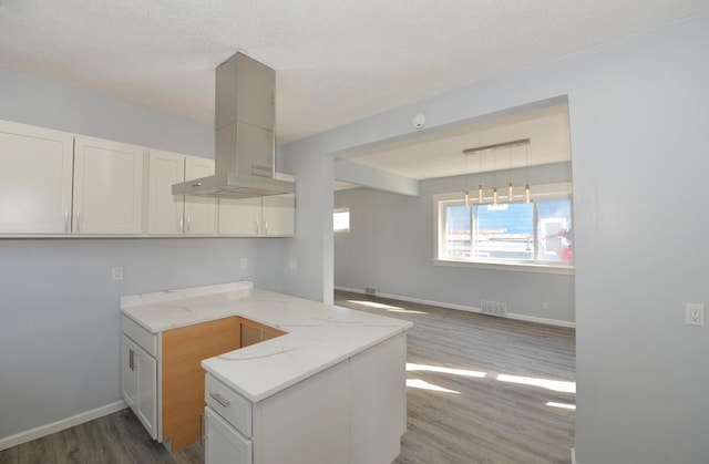 kitchen featuring decorative light fixtures, white cabinets, dark hardwood / wood-style flooring, island exhaust hood, and kitchen peninsula