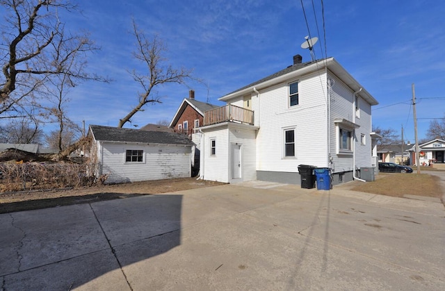 back of property with a balcony, central AC, and an outdoor structure