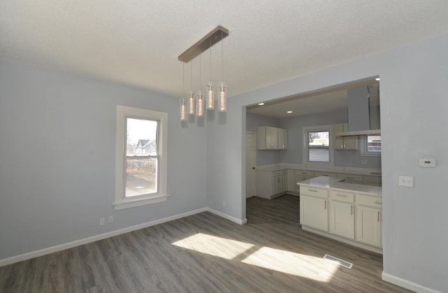 kitchen with pendant lighting, stovetop, dark hardwood / wood-style flooring, wall chimney range hood, and a textured ceiling