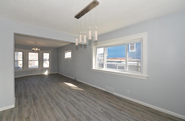 unfurnished room featuring dark hardwood / wood-style flooring, a chandelier, and a textured ceiling