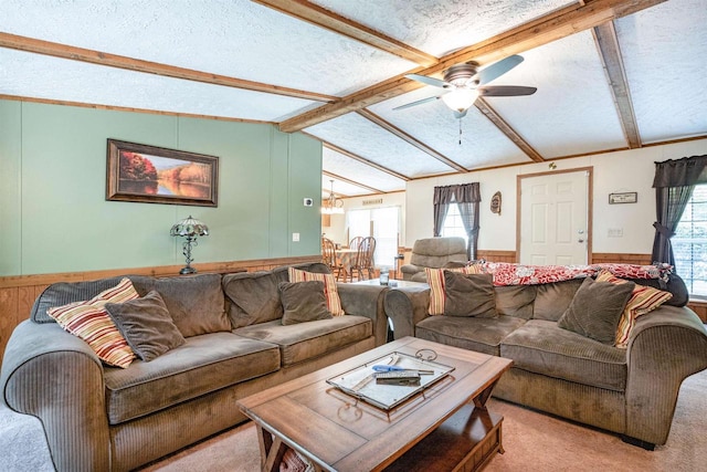 carpeted living room with wood walls, ceiling fan with notable chandelier, a textured ceiling, and vaulted ceiling with beams