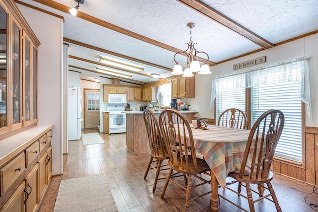 dining area featuring crown molding, light wood-type flooring, a textured ceiling, and beam ceiling