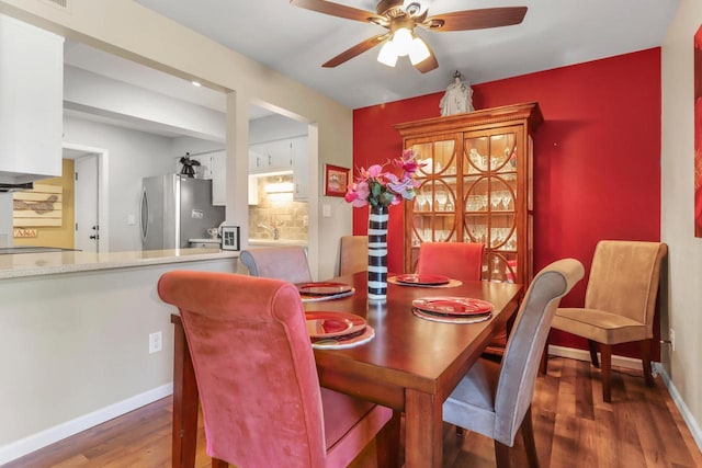 dining room with ceiling fan, sink, and dark hardwood / wood-style flooring