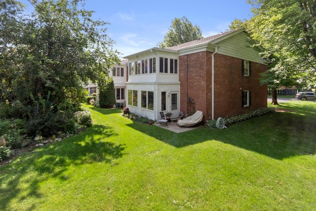 back of property with a yard, a sunroom, and a patio