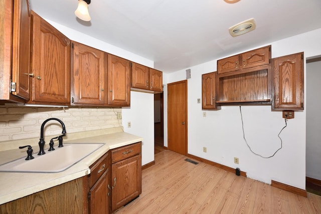 kitchen featuring sink, light hardwood / wood-style flooring, and backsplash