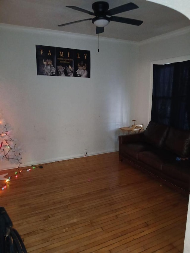 unfurnished living room featuring wood-type flooring, ceiling fan, and crown molding