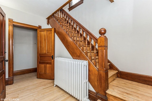 staircase featuring hardwood / wood-style flooring and radiator heating unit