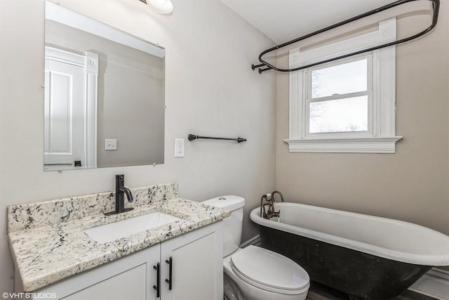 bathroom featuring vanity, a tub to relax in, and toilet