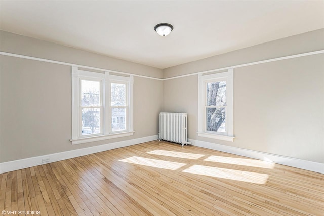 unfurnished room featuring radiator and light wood-type flooring