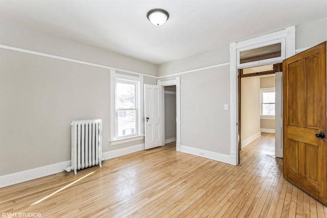 unfurnished room with radiator and light wood-type flooring