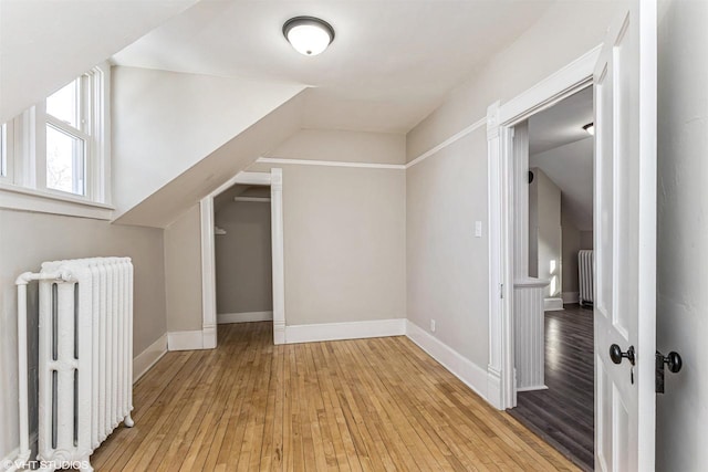 additional living space featuring lofted ceiling, radiator heating unit, and light hardwood / wood-style floors