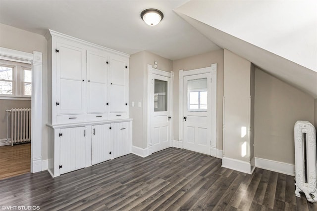 interior space with lofted ceiling, dark wood-type flooring, and radiator heating unit