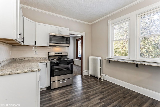 kitchen with radiator, ornamental molding, white cabinets, and appliances with stainless steel finishes