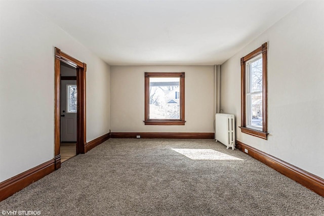 empty room with carpet flooring, radiator, and a wealth of natural light