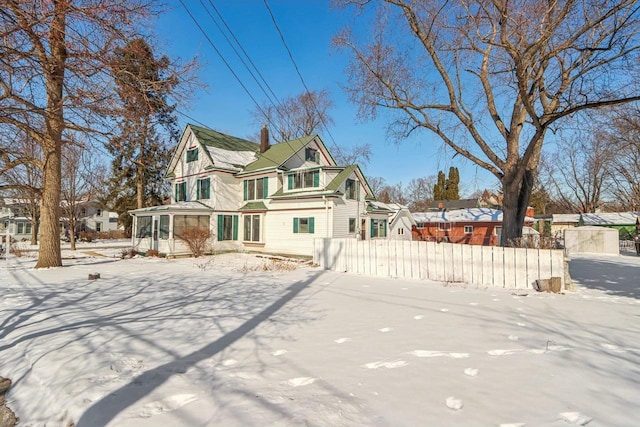 view of front of house featuring a chimney, fence, and a residential view