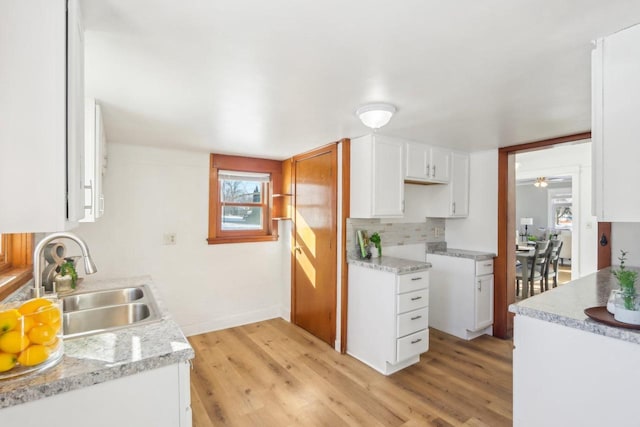 kitchen with backsplash, light wood-type flooring, a sink, and white cabinets