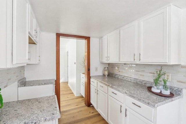 kitchen with light wood-type flooring, decorative backsplash, and white cabinets