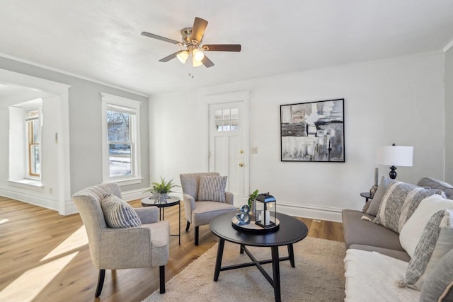 living area with light wood-type flooring, baseboards, and a ceiling fan