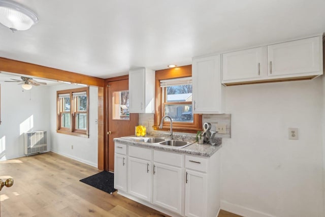 kitchen with light wood-style floors, white cabinetry, light countertops, and a sink