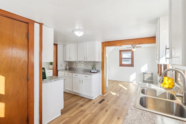 kitchen with ceiling fan, a sink, light wood-style floors, white cabinets, and tasteful backsplash