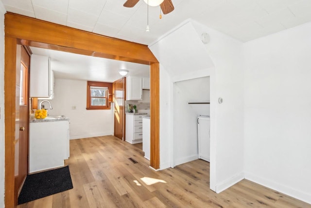 kitchen with light countertops, light wood-style floors, a ceiling fan, white cabinets, and baseboards