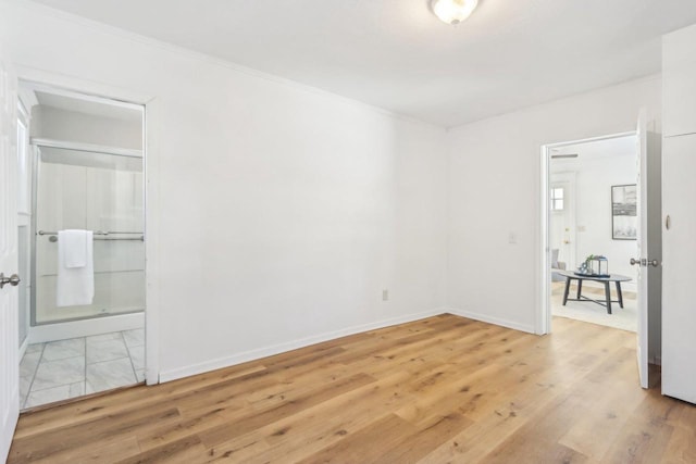 unfurnished bedroom with ensuite bathroom, ornamental molding, light wood-type flooring, and baseboards