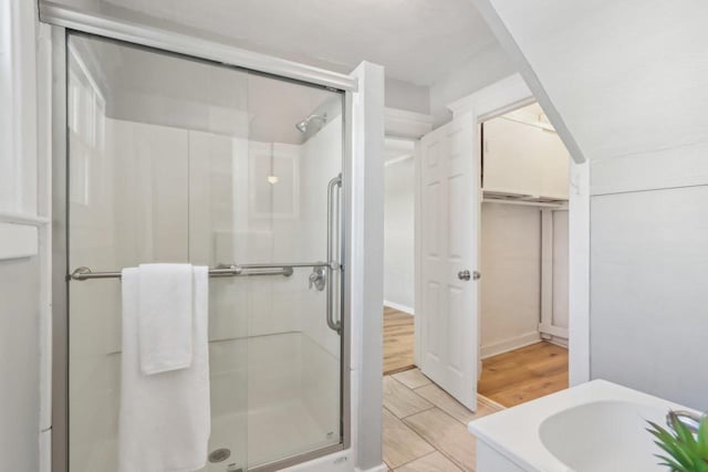 full bath with a sink, a closet, a stall shower, and wood finished floors