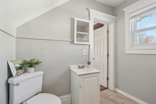 half bathroom featuring wood finished floors, vanity, toilet, and baseboards