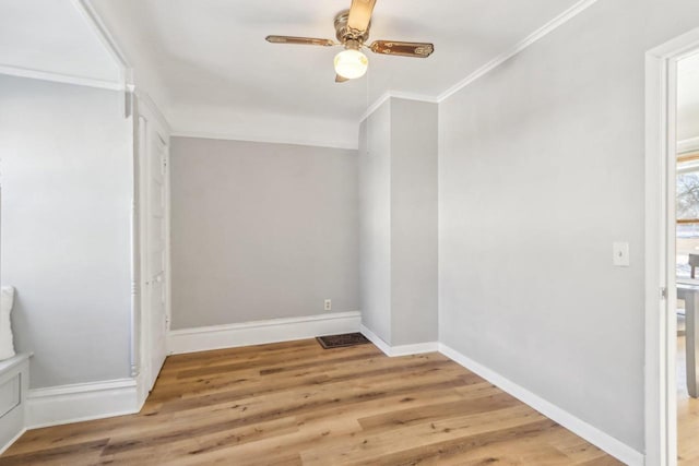 spare room featuring light wood-type flooring, baseboards, and crown molding