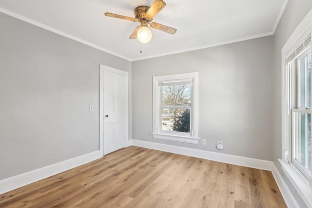 empty room with crown molding, light wood finished floors, a ceiling fan, and baseboards