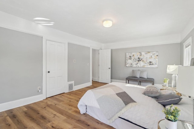 bedroom featuring visible vents, baseboards, and wood finished floors