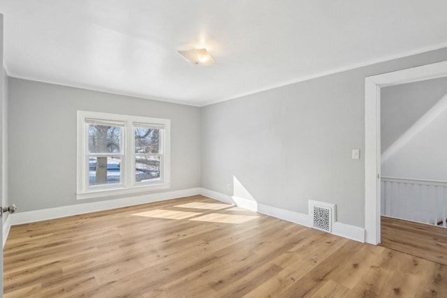 unfurnished room featuring light wood-style floors, visible vents, and baseboards