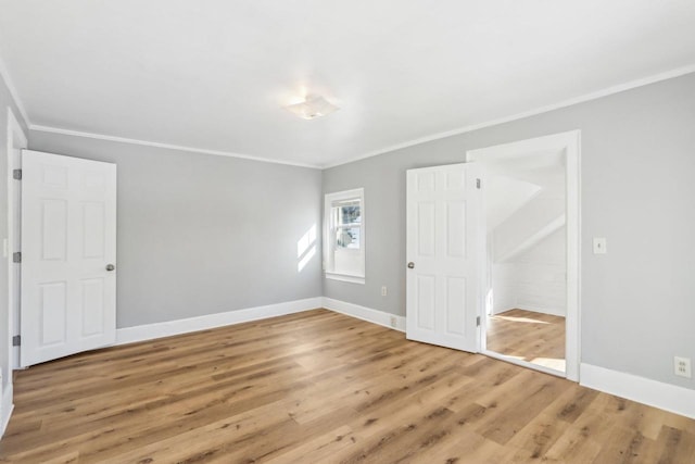 unfurnished bedroom with crown molding, baseboards, and wood finished floors