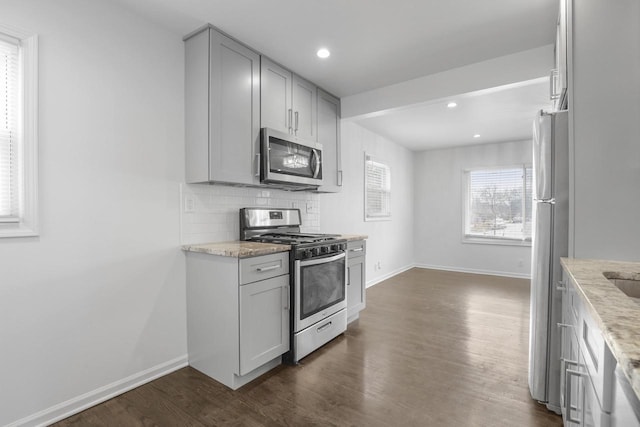 kitchen featuring light stone counters, stainless steel appliances, and gray cabinets