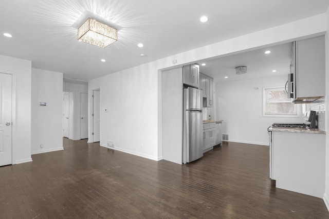 kitchen with dark wood-type flooring, appliances with stainless steel finishes, light stone countertops, and gray cabinetry