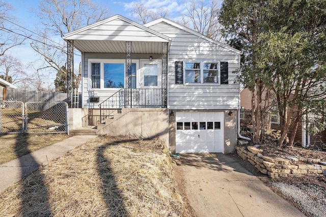 view of front of house featuring a gate, a porch, fence, concrete driveway, and a garage