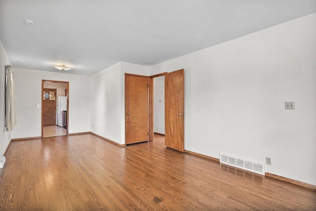 empty room with visible vents, baseboards, and wood finished floors