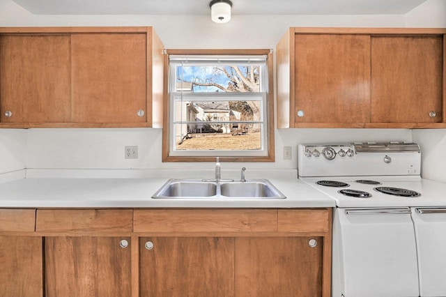 kitchen with a sink, brown cabinets, light countertops, and electric stove