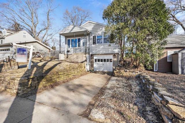 view of front facade featuring a garage, driveway, and fence