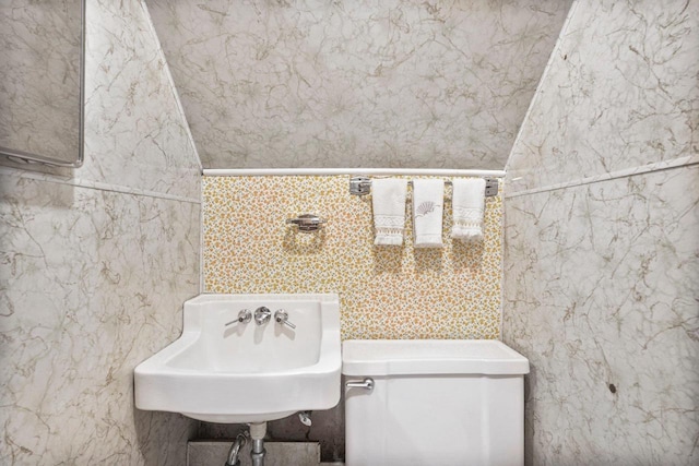 half bathroom with a sink, toilet, and tile walls