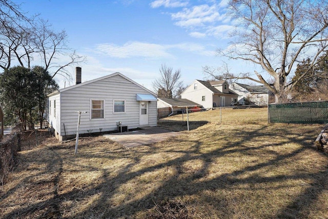 back of property with fence, a lawn, central AC, and a chimney