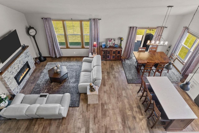 living room with hardwood / wood-style floors, a stone fireplace, and plenty of natural light