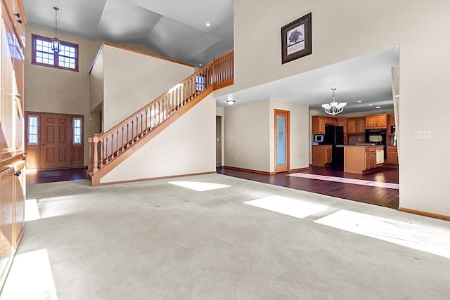 unfurnished living room featuring a notable chandelier, dark carpet, and a high ceiling