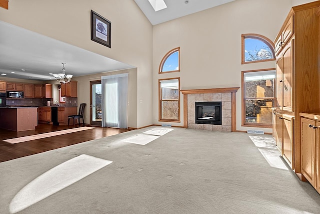 carpeted living room featuring sink, a towering ceiling, a fireplace, and a notable chandelier