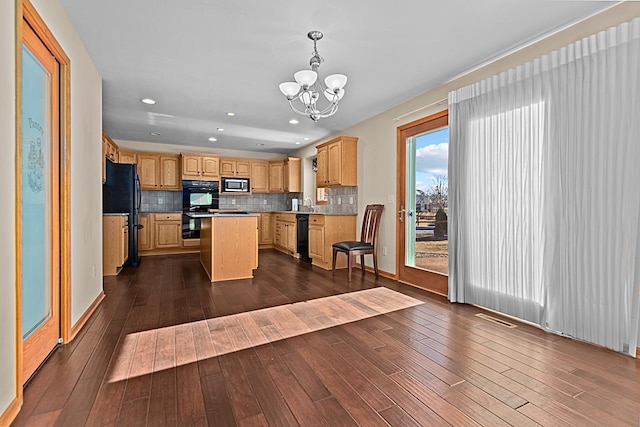 kitchen with dark hardwood / wood-style floors, decorative light fixtures, tasteful backsplash, a center island, and black appliances