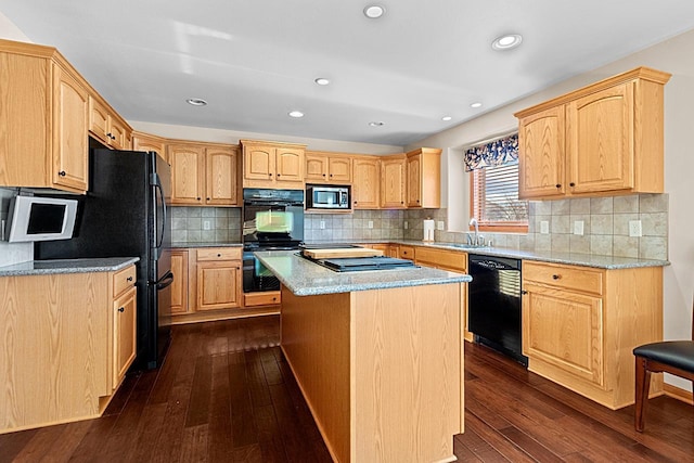 kitchen featuring sink, a center island, dark hardwood / wood-style flooring, light stone countertops, and black appliances