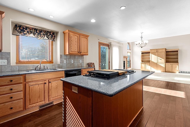 kitchen with tasteful backsplash, dishwasher, sink, a center island, and dark wood-type flooring