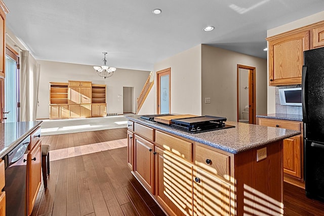 kitchen with decorative light fixtures, a chandelier, dark hardwood / wood-style floors, a kitchen island, and black appliances